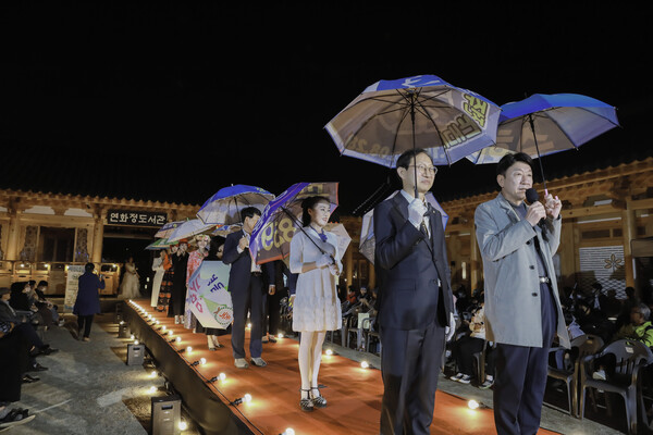 폐플래카드로 만든 우산을 들고 내빈 20여 명이 우산쇼를 펼치고 있다.