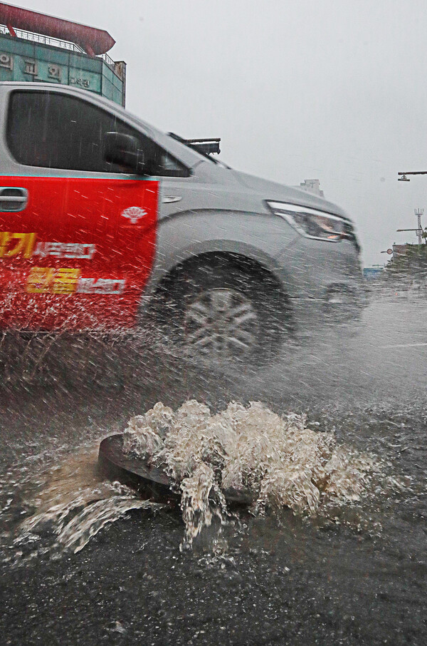 새벽부터 전북 전역에 세찬 비가 내린 14일 오전 완주군 삼례사거리에서 빗물이 역류하면서 맨홀 뚜껑을 반쯤 열어놔 운전자들에게 위협이 되고 있다. 