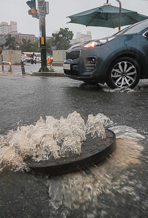새벽부터 전북 전역에 세찬 비가 내린 14일 오전 완주군 삼례사거리에서 빗물이 역류하면서 맨홀 뚜껑을 반쯤 열어놔 운전자들에게 위협이 되고 있다. 
