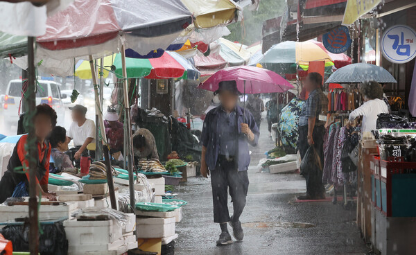 전주시에 호우주의보가 내려진 26일 전주시 중앙시장에서 한 시민이 비를 피하기 위해 우산을 들고 걸음을 재촉하고 있다.
