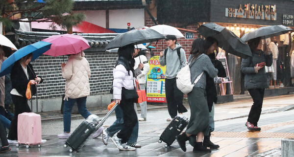 봄을 재촉하는 비가 내린 15일 전주 한옥마을에서 관광객들이 우산을 받고 서둘러 이동을 하고 있다./이원철기자