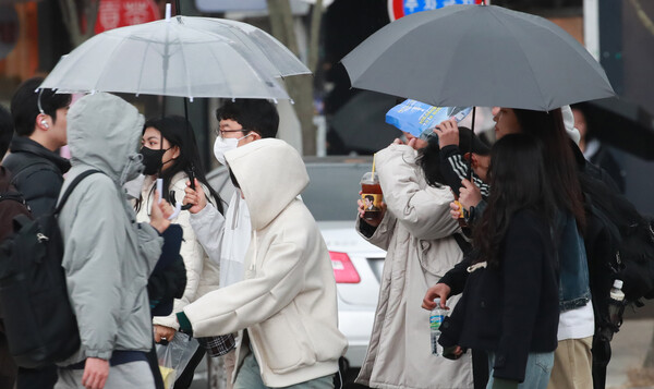 강한 바람과 함께 꽃샘추위가 찾아온 19일 전주시 덕진동에서 시민들이 갑자기 내린 비에 모자와 우산을 쓰고 서둘러 이동을 하고 있다./이원철기자