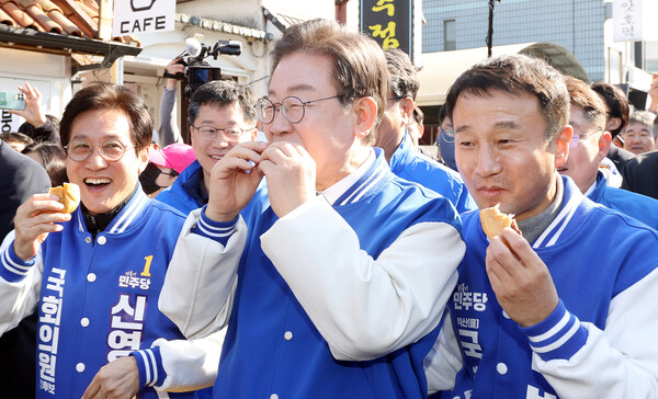 이재명 더불어민주당 대표가 21일 군산시 근대문화역사거리를 찾아 거리 인사를 하던 중 지지자가 준 빵을 먹고 있다.