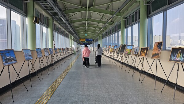 ▲ 전시된 사진작품을 둘러보며 지나가고 있다.